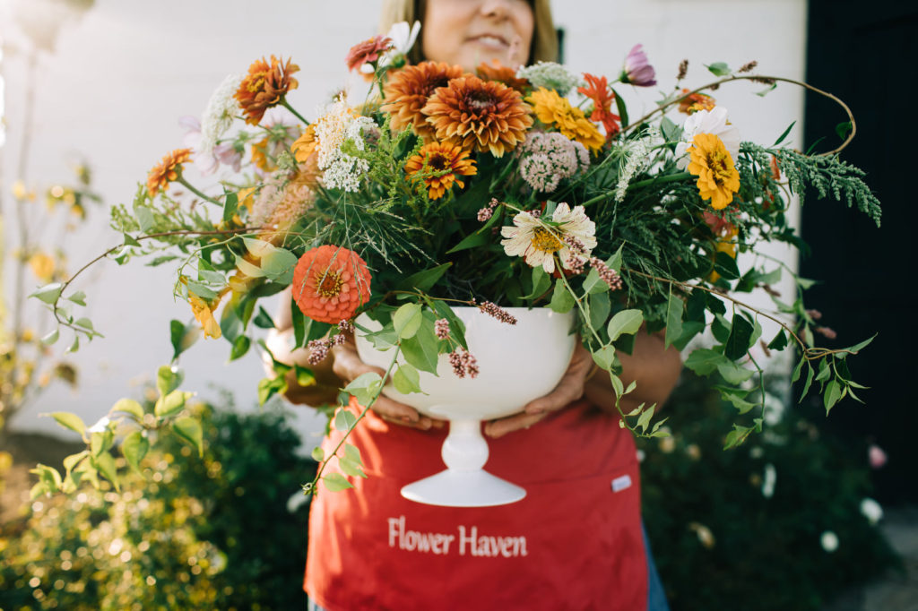 Melissa LaRose, owner of Flower Haven, holding large vase of flowers