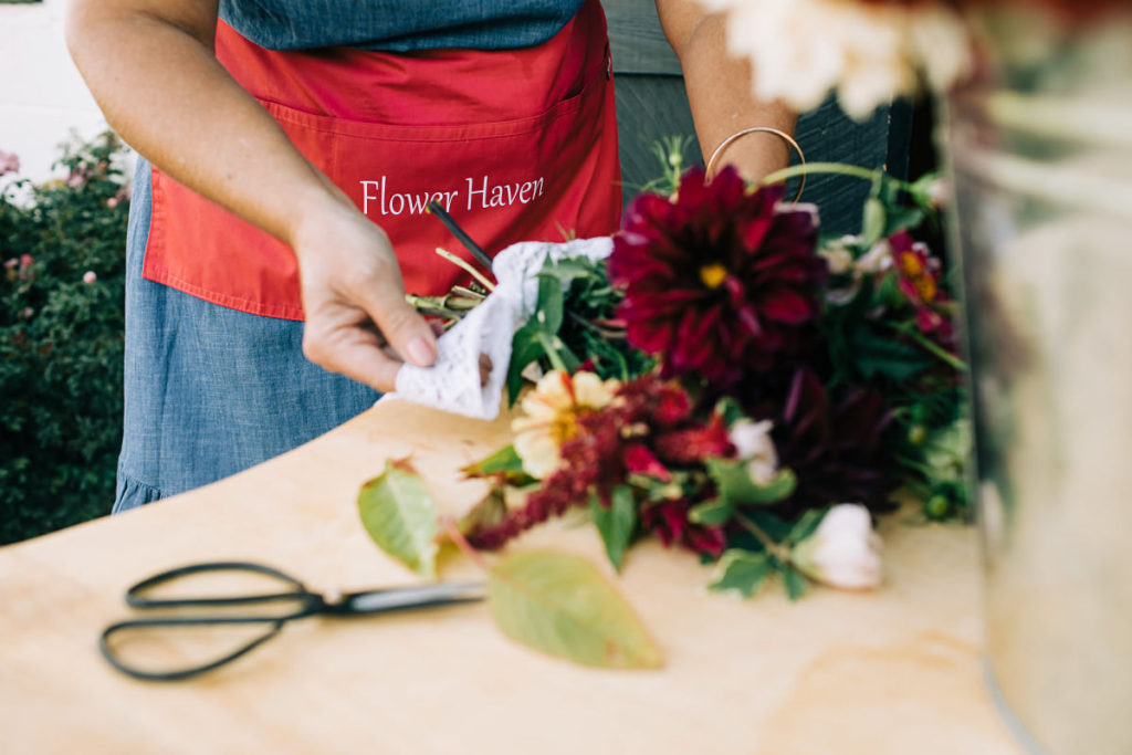 Melissa LaRose, owner of Flower Haven, tying bow on bouquet